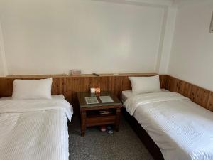 two beds in a room with a table between them at 雲台客棧民宿 in Nangan +8 photos