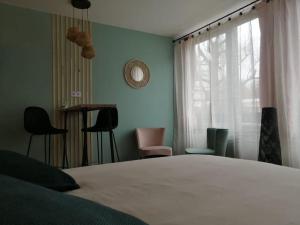 ein Schlafzimmer mit einem Bett und Stühlen sowie einem Fenster in der Unterkunft Studio neuf - parking - 3 Epis proche Turckheim in Turckheim