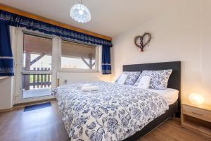 Schlafzimmer mit einem Bett mit einer blauen und weißen Bettdecke in der Unterkunft Penzion POSADA in Podivín