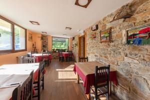 ein Restaurant mit Tischen und Stühlen und einer Steinmauer in der Unterkunft LA PANDELA in Las Herrerías