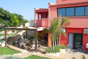 czerwony budynek z patio ze stołami i krzesłami w obiekcie Pozzillo San Rocco w mieście Arnesano