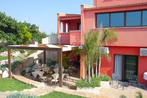 a red building with a patio with tables and chairs at Pozzillo San Rocco in Arnesano