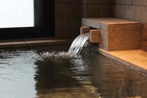 een fontein in een gebouw waar water uit komt bij Nikko Nishimachi Club in Nikko