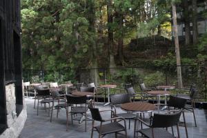 an outdoor patio with tables and chairs and trees at Nikko Nishimachi Club in Nikko