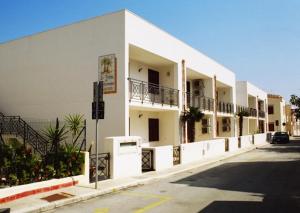 a white building with balconies on the side of a street at Le Palme Di Conturrana in San Vito lo Capo