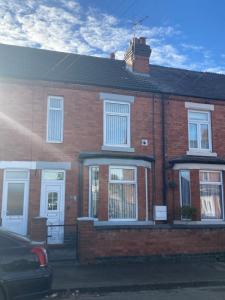 una casa de ladrillo con ventanas blancas y un coche aparcado delante en Cheshire Home Stays, en Church Coppenhall