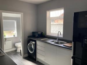 a kitchen with a sink and a washing machine at Cheshire Home Stays in Church Coppenhall +17 photos