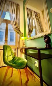 a green chair sitting next to a desk with a lamp at Elegant apartment in Kosice in Košice