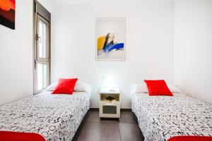 2 Betten in einem Zimmer mit zwei roten Kissen in der Unterkunft Mare Home - Beach & City in Las Palmas de Gran Canaria