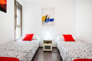 two beds in a room with two red pillows at Mare Home - Beach & City in Las Palmas de Gran Canaria