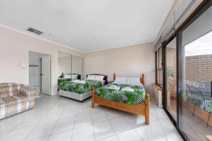 Habitación con 2 camas y sofá en Tuggeranong Short Stay #10 - Sleeps 6, en Tuggeranong