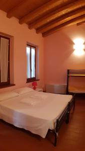 a bedroom with a large white bed with two windows at Ostello Molino Di Basso in Roccafranca