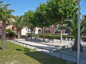 park z ławkami i palmami oraz budynek w obiekcie T1 bis avec piscine w mieście Canet-en-Roussillon