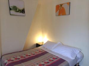 - un petit lit dans une chambre avec 2 photos sur le mur dans l'établissement Hotel Restaurant Tokyo, à Trouville-sur-Mer