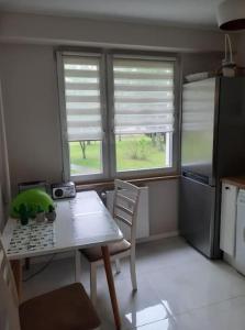 a small kitchen with a table and two windows at W pełni wyposażone mieszkanie in Augustów +5 photos
