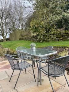 a patio table and chairs with a potted plant on it at Daisy Cottage in Keighley