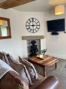 a living room with a couch and a clock on the wall at Daisy Cottage in Keighley