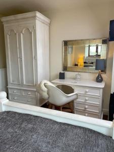 a bathroom with a vanity and a chair and a mirror at Daisy Cottage in Keighley
