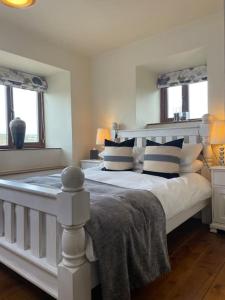 a bedroom with a white bed with blue and white pillows at Daisy Cottage in Keighley