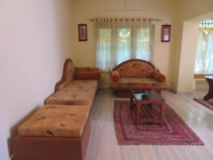 a living room with two couches and a rug at NISARGA in Yercaud