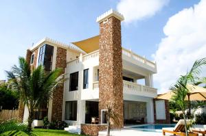 a large white house with a tall pillar at ZANA DIANI VILLAS in Ukunda
