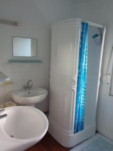 y baño blanco con lavabo y ducha. en Gîte Le Coquillage, 50m de la mer, en Saint-Germain-sur-Ay