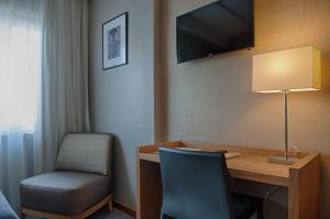 Hotel Oslo في كويمبرا: غرفة بها مكتب وكرسي وتلفزيون
