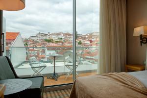 a bedroom with a view of a city from a window at Hotel Oslo in Coimbra