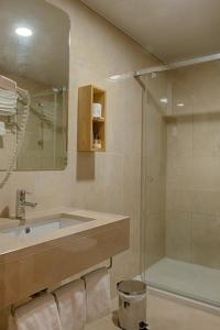 y baño con lavabo y ducha. en Hotel Oslo en Coímbra