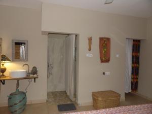 a room with a bathroom with a shower and a table at POMBO KUNDA Room in Sanyang