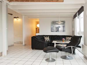 エーベルトフトにある10 person holiday home in Ebeltoftのリビングルーム(黒いソファ、テーブル付)