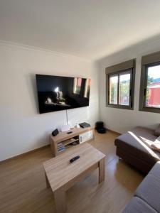 een woonkamer met een bank en een tv aan de muur bij Apartamento Almogaren in Valsequillo