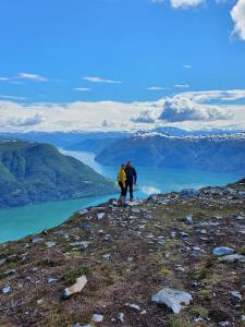 2 personnes debout au sommet d'une montagne surplombant un lac dans l'établissement Molden 2-fjellutsikt og jacuzzi tilgang., à Luster