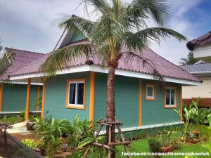 a green house with a palm tree in front of it at Coconut Homes Khao Lak in Khao Lak