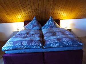 a bed with blue comforter and pillows on it at Ferienhaus Schöne Aussicht in Esch