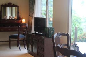 a room with a desk with a television and a piano at Highwood Park B&B Guest Lodge in Maleny