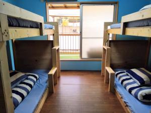 2 Etagenbetten in einem Zimmer mit Fenster in der Unterkunft TONARINO Hostel for Backpackers in Kōbe