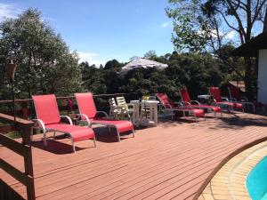 a deck with chairs and a table and an umbrella at Hospedagem Spa da Alma in Monte Verde