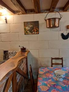 La Chauvellière, un écrin de verdure dans un cadre historique في Beaumont-la-Ronce: غرفة طعام مع طاولة ودلو على الحائط