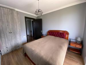 sypialnia z łóżkiem z czerwonym zagłówkiem i komodą w obiekcie Дом на пляже Black sea House w Kobuleti