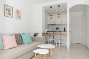 sala de estar y cocina con sofá y mesas en Naia House Lanzarote, en Puerto del Carmen