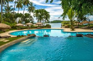 ein großer Pool neben einem Wasserkörper in der Unterkunft Pearl Farm Beach Resort in Samal