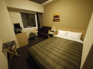 Hotel Route Inn Ishinomaki Chuo في إيشينوماكي: غرفه فندقيه بسرير واريكه