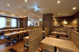uma sala de jantar com mesas e cadeiras de madeira em Hotel Route Inn Ishinomaki Chuo em Ishinomaki
