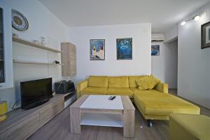 a living room with a yellow couch and a tv at Apartment Renata in Postira