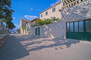 a brick building with green garage doors on a street at Apartment Renata in Postira