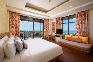 a bedroom with a large bed and a balcony at Karon Phunaka Resort in Karon Beach