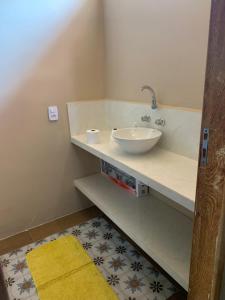 uma casa de banho com um lavatório e um tapete amarelo em Pousada Fiori em Nova Friburgo