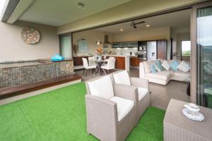 a living room with white chairs and a kitchen at SLEEP IN MAURITIUS in Grand Baie
