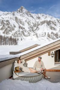 萨姆瑙恩Relais & Châteaux Chasa Montana的两个人坐在白雪皑皑的山上。 更多99张照片
